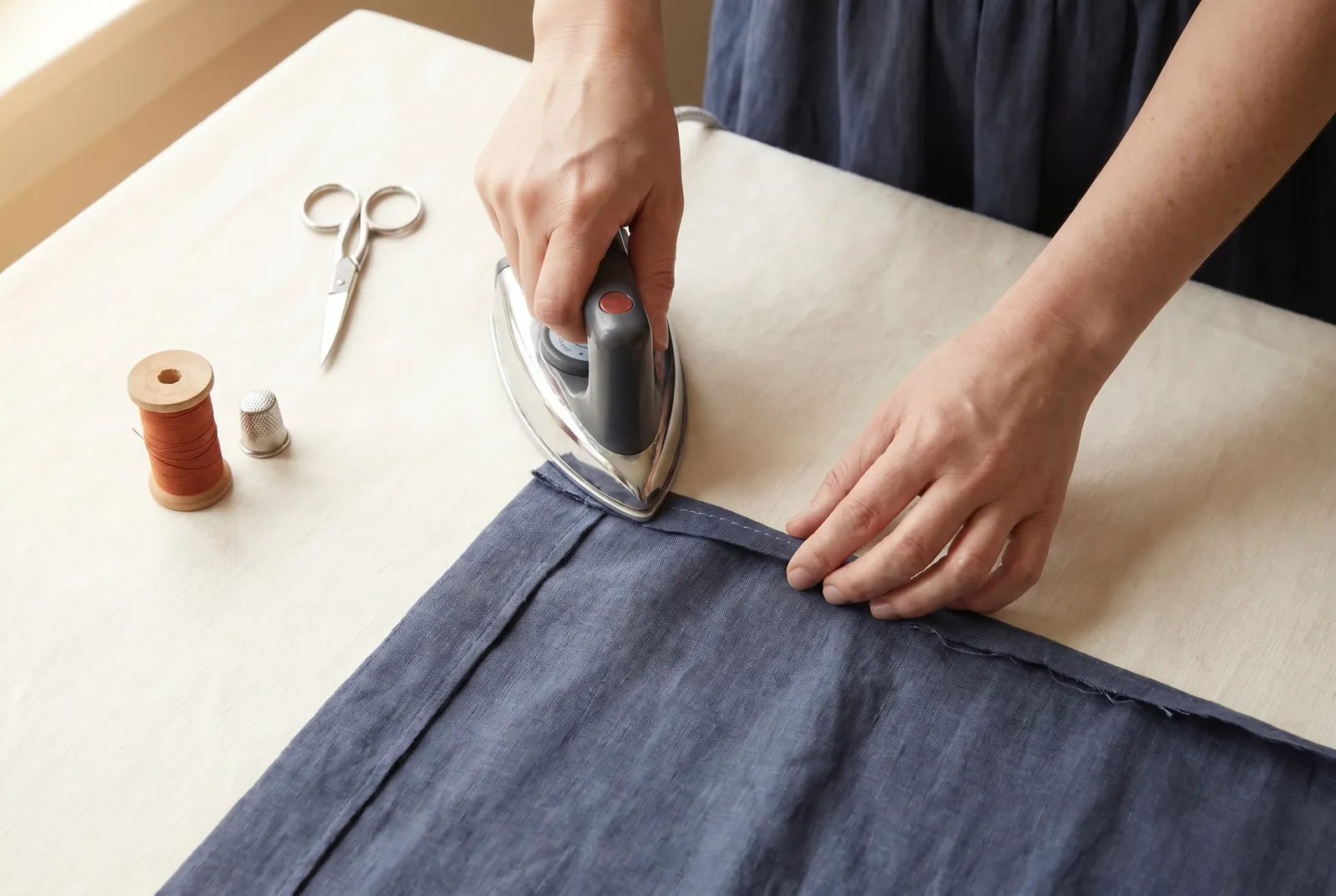 Photo: Turn the raw cut edge under 6 mm (1/4 in) toward the wrong side all around, pressing the fold flat as you go; folding the raw edge under this way encloses it s…
