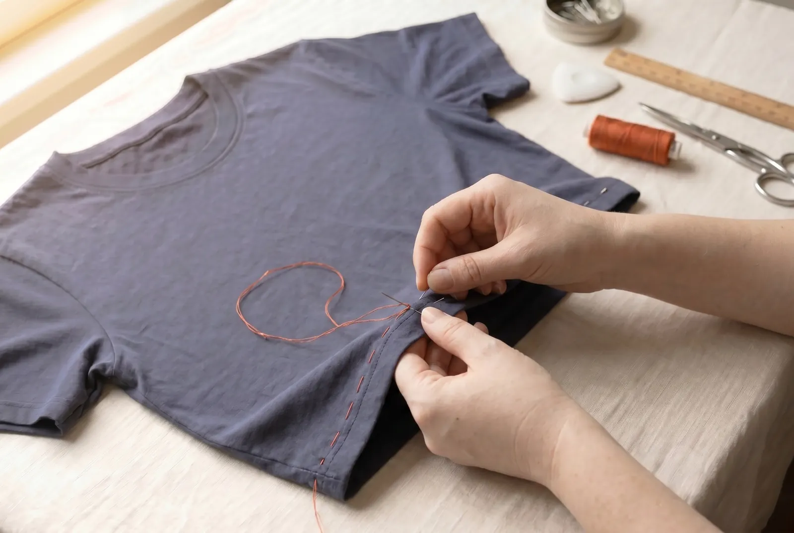 Photo: Baste the hem with long running stitches to hold the fold while you sew, pulling out each pin as you reach it.