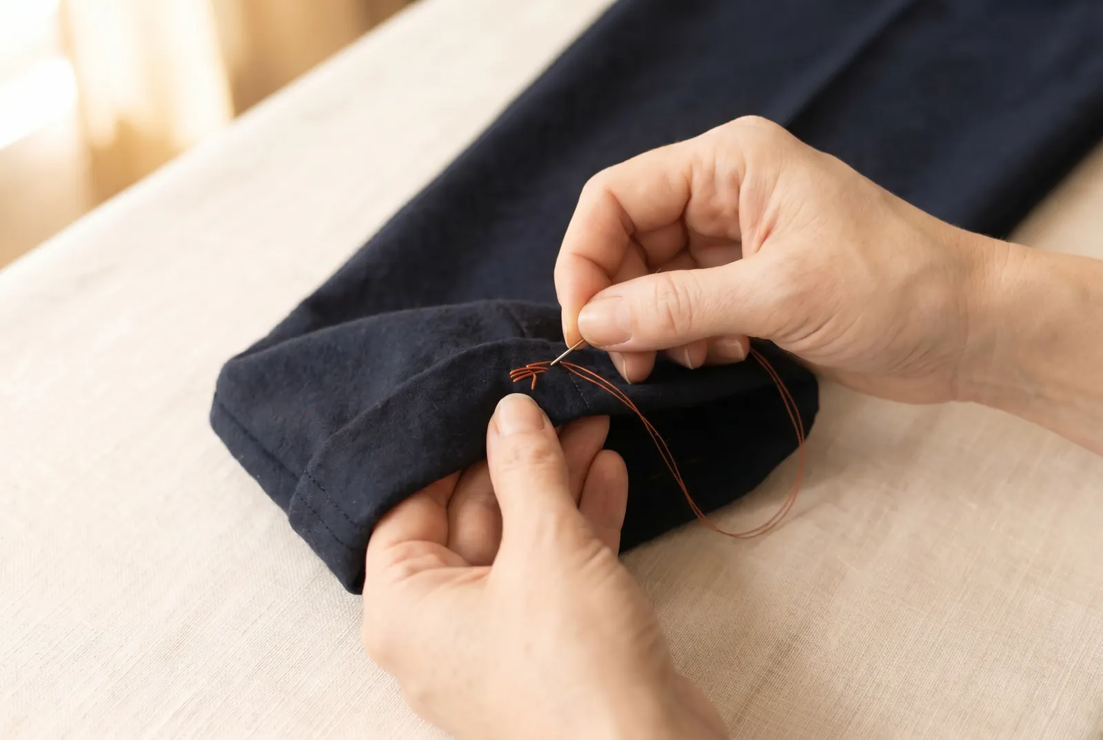 Photo: When you reach the start, fasten the thread off inside the fold with two or three small stitches worked into the hem, never with a knot on the outside.