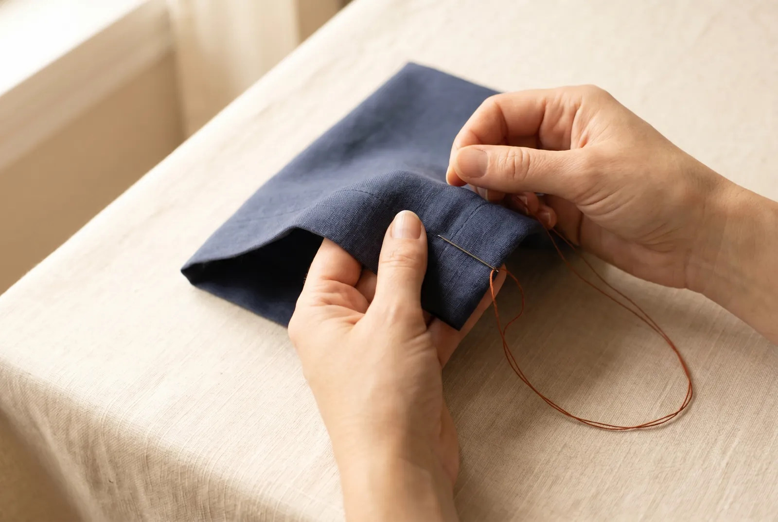 Photo: Hold the folded hem edge across the cushion of your left forefinger, kept in place by your thumb, and work from right to left.