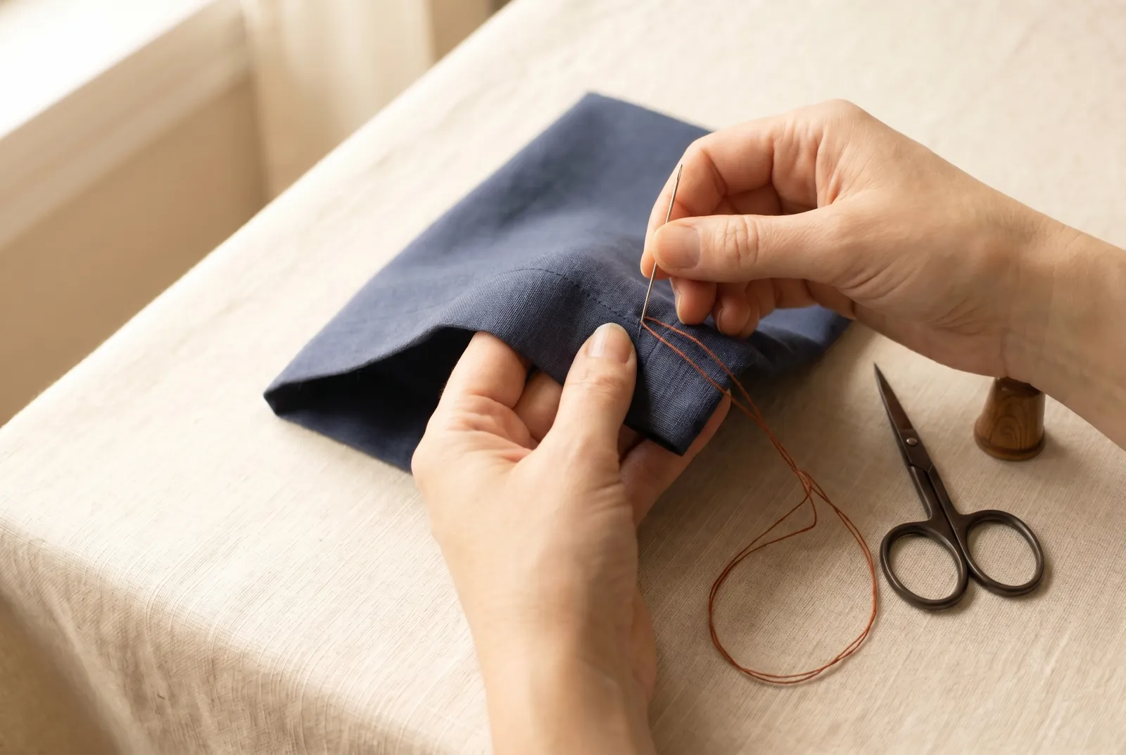 Photo: For the hemming stitch, point the needle toward your left shoulder, take up one or two threads of the garment immediately below the fold, and in the same motio…