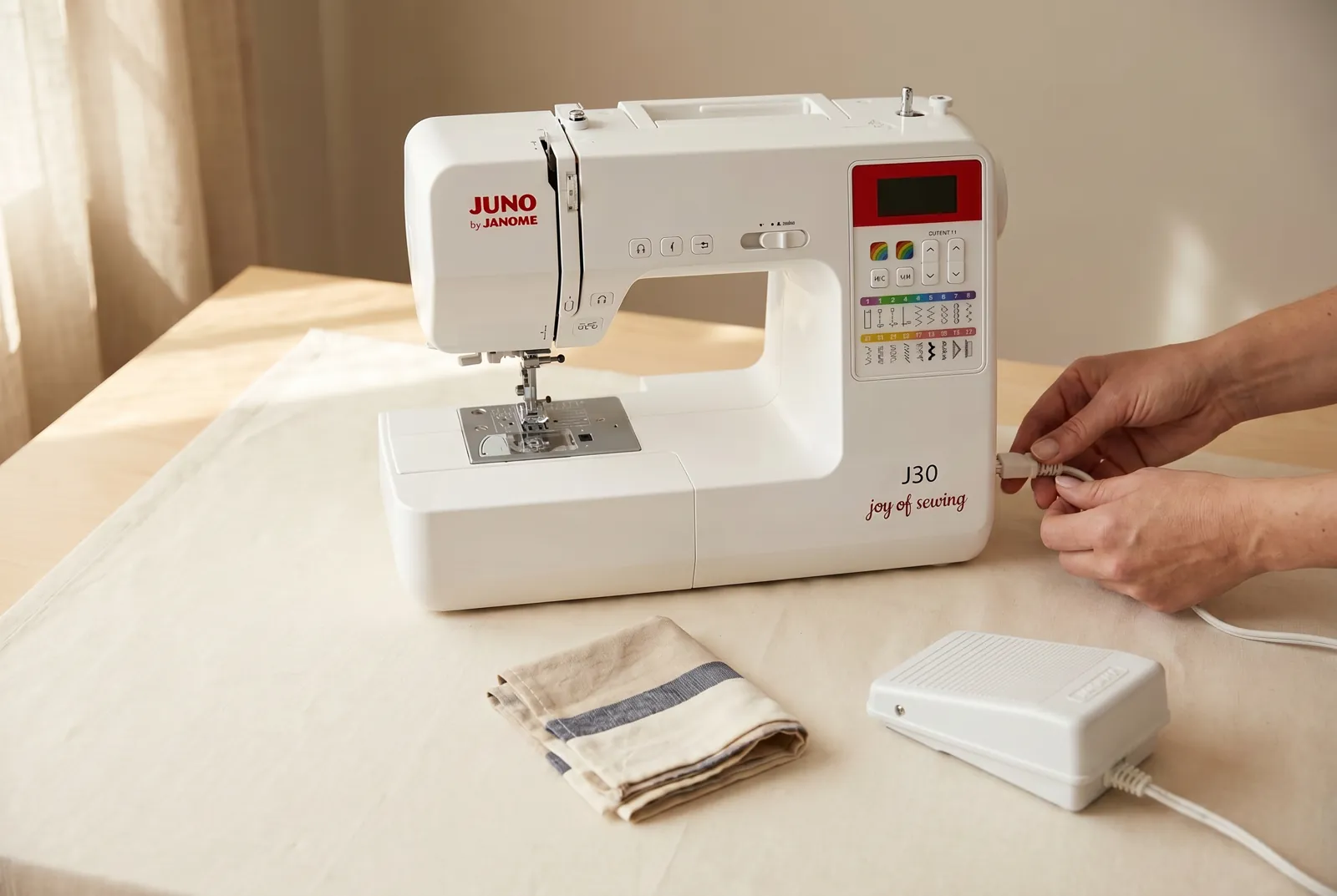 Photo: Set the J30 on a stable table with the flat foot pedal on the floor in front of your chair, leaving both hands free to reach the machine.