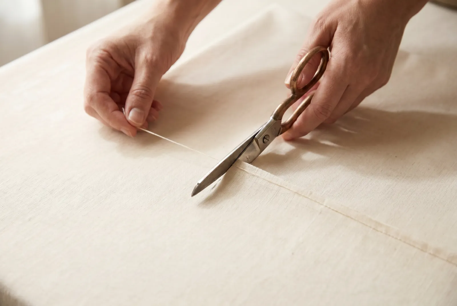 Photo: Straighten the cut edge before you sew: pick up one crosswise thread near the end, draw it until it leaves a line across the cloth, and cut on that line.