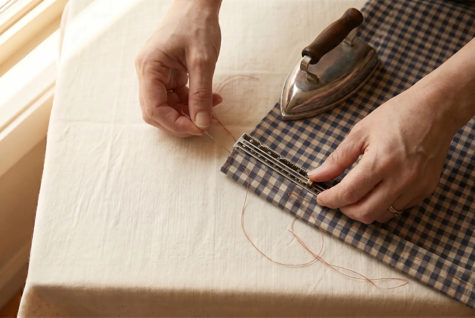 Photo: Turn the bottom hem two inches (5 cm) deep, making a quarter-inch (6 mm) first fold measured with a gauge so the depth stays even the whole way across, and bas…