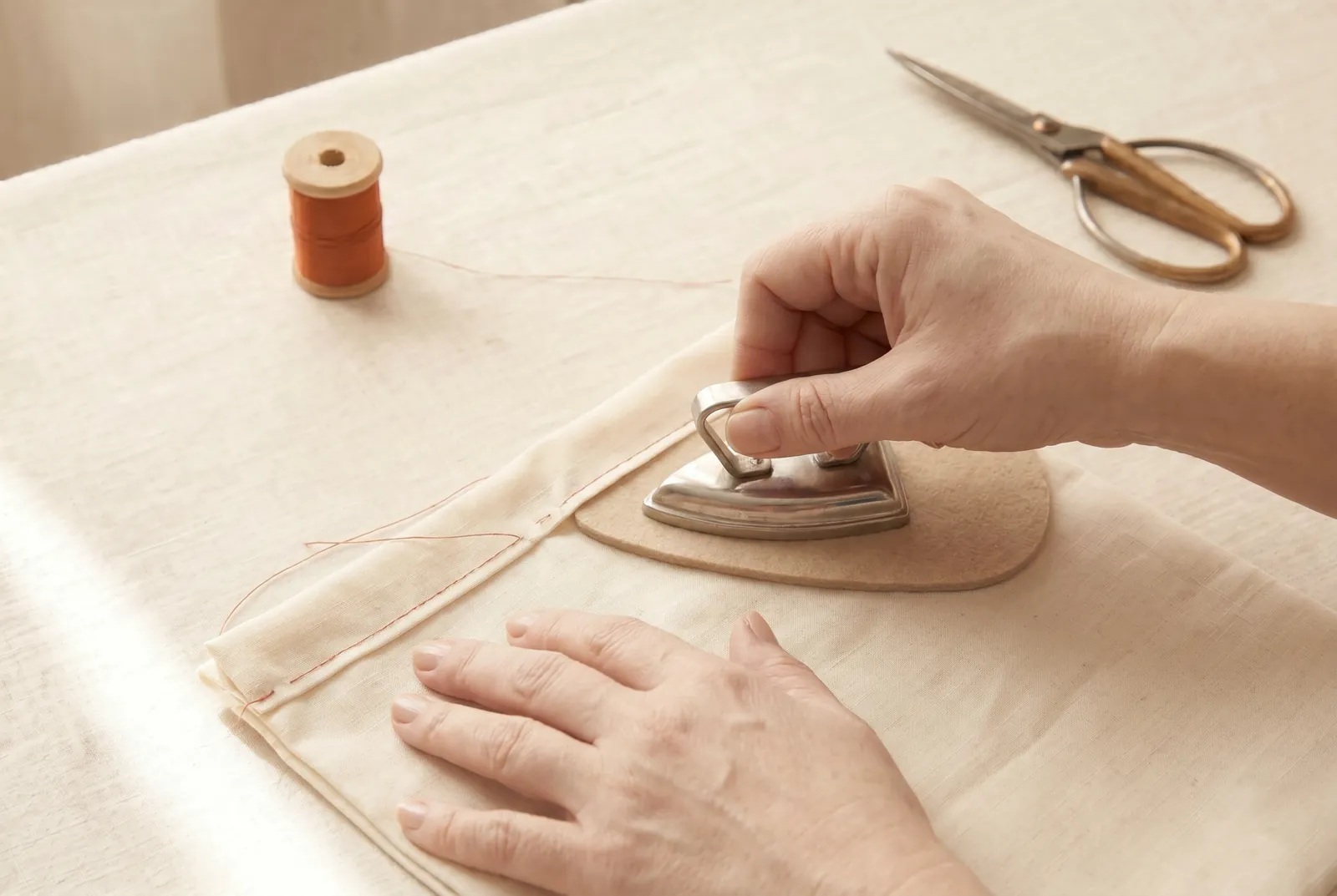 Photo: Turn the top edge to the wrong side 6 mm (1/4 in), then again 3 cm (1 1/4 in); baste the fold, then stitch it down along its lower edge.