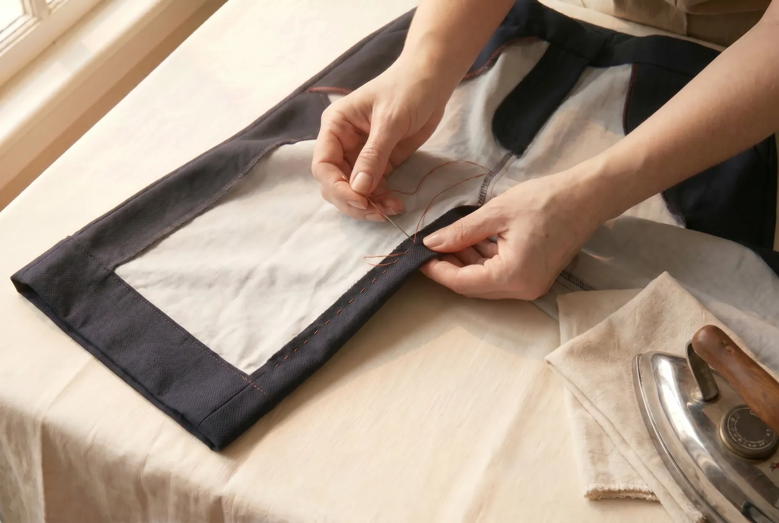 Photo: Finish each raw edge so the cut cloth cannot ravel: turn the edge under about 6 mm (1/4 in) and hem it flat with small slanting stitches worked right to left,…