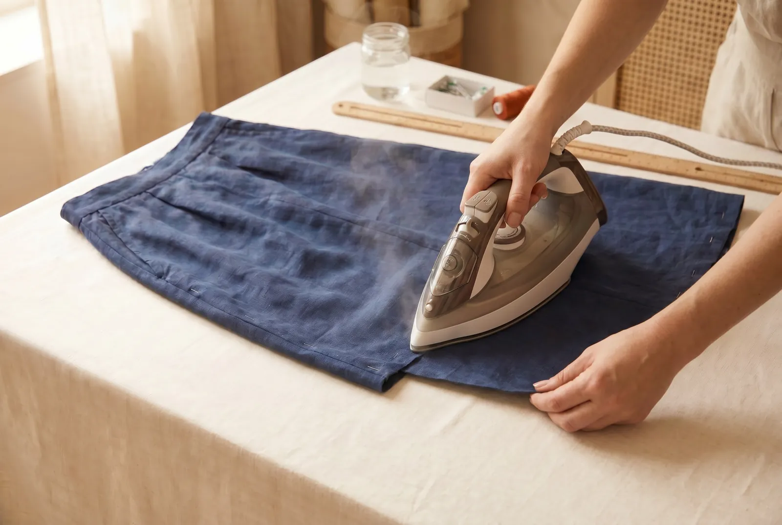 Photo: Fold the raw cut edge under toward the wrong side by 6 mm (1/4 in) and press the fold with a warm iron as you work around the skirt.